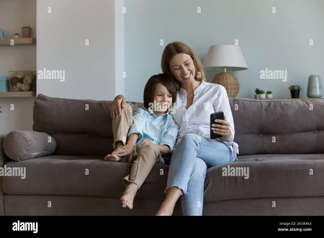 Happy pretty mom and cute little son relaxing on sofa Stock Photo