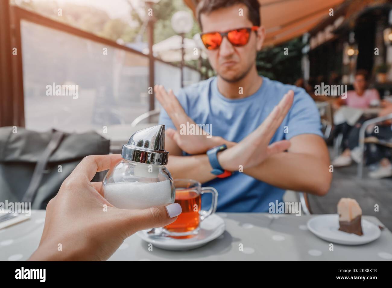 Man is on a healthy diet and refuses to add sugar to his glass of tea. The concept of diseases from an excess of fast carbohydrates and diabetes Stock Photo
