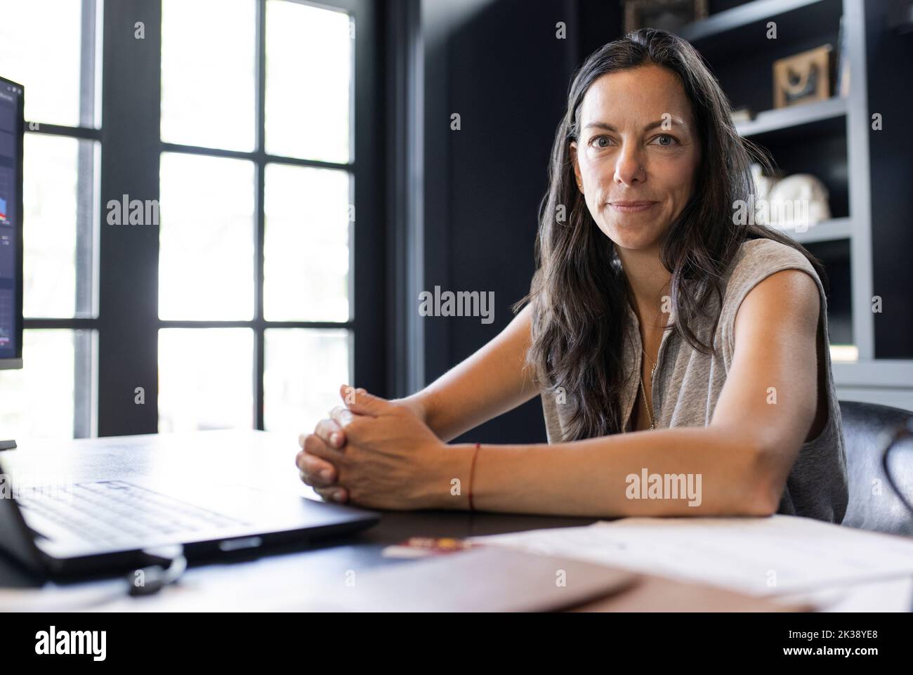 Portrait confident woman working from home at desk in home office Stock