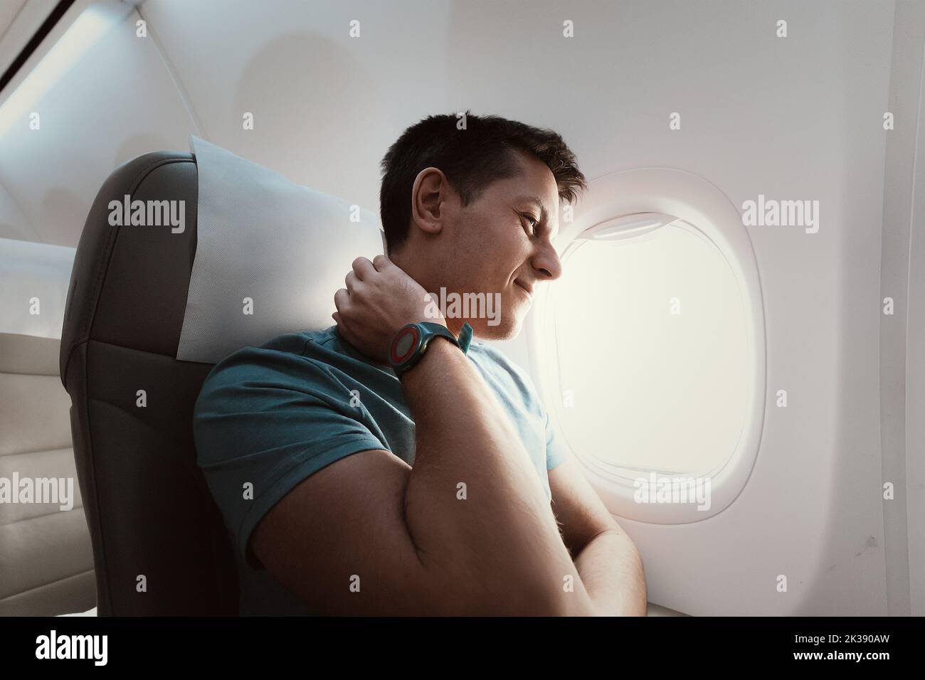 A man suffers from severe neck pain during a long flight in an