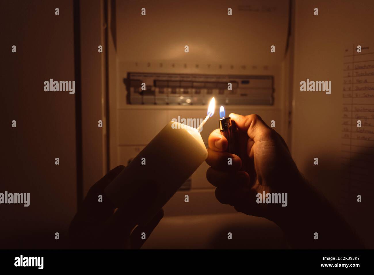 Power Failure In The Apartment, Man Shines Candlelight And Checks The Fuse Box. Electricity, Power Failure, Blackout Concept Stock Photo