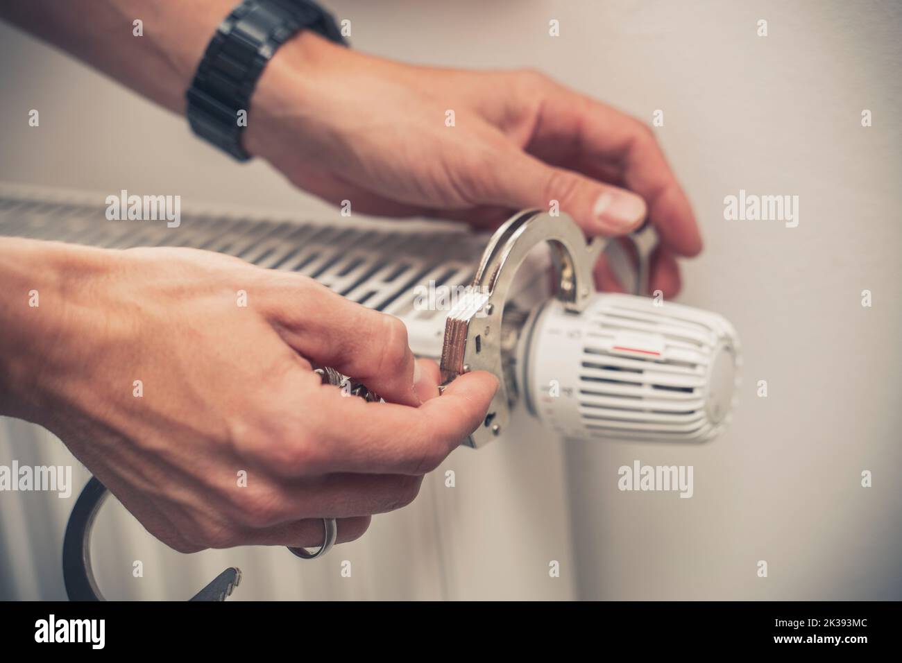 25 September 2022: Hand Locks Radiator With Handcuffs, Symbol Image Rising Costs For Electricity, Heating And Gas Stock Photo