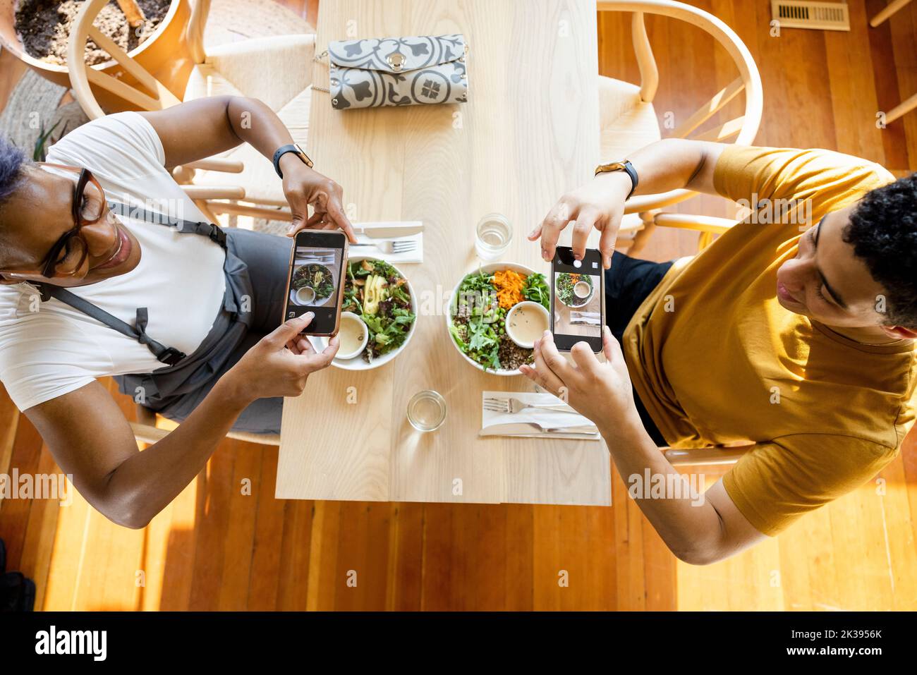 Overhead view of customers taking photograph of food in cafe Stock
