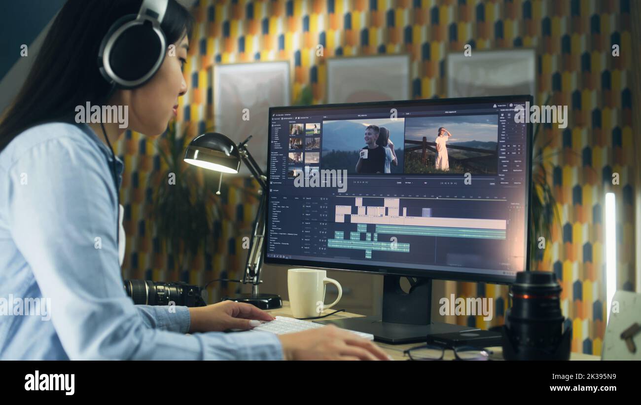 Concentrated asian woman sitting at the table and editing video for ...