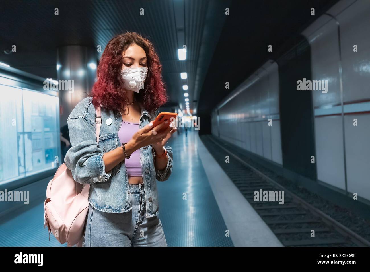 Asian girl wears a facial respiratory mask during the Covid-19 coronavirus pandemic and looks at the route of the trip to the place in the smartphone Stock Photo
