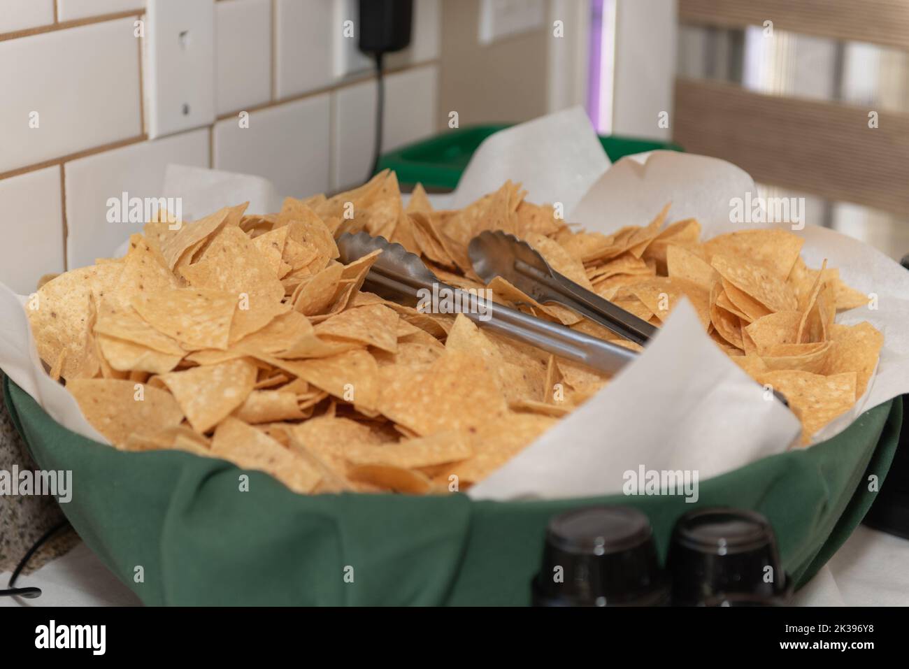 Large bowl of chips with serving tongs ready for the party guests to