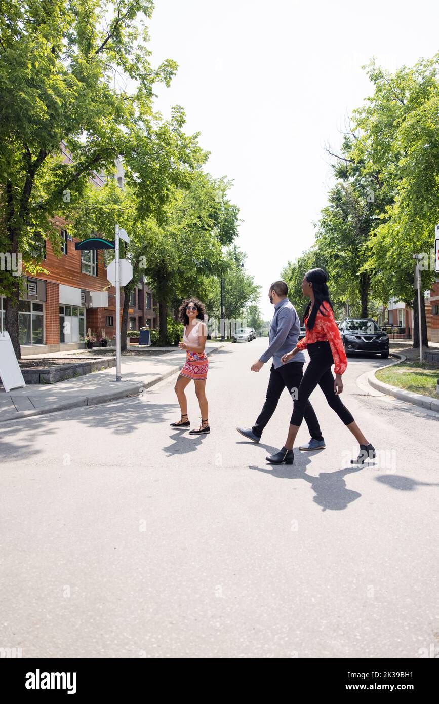 Cheerful friends crossing road in suburbs Stock Photo Alamy
