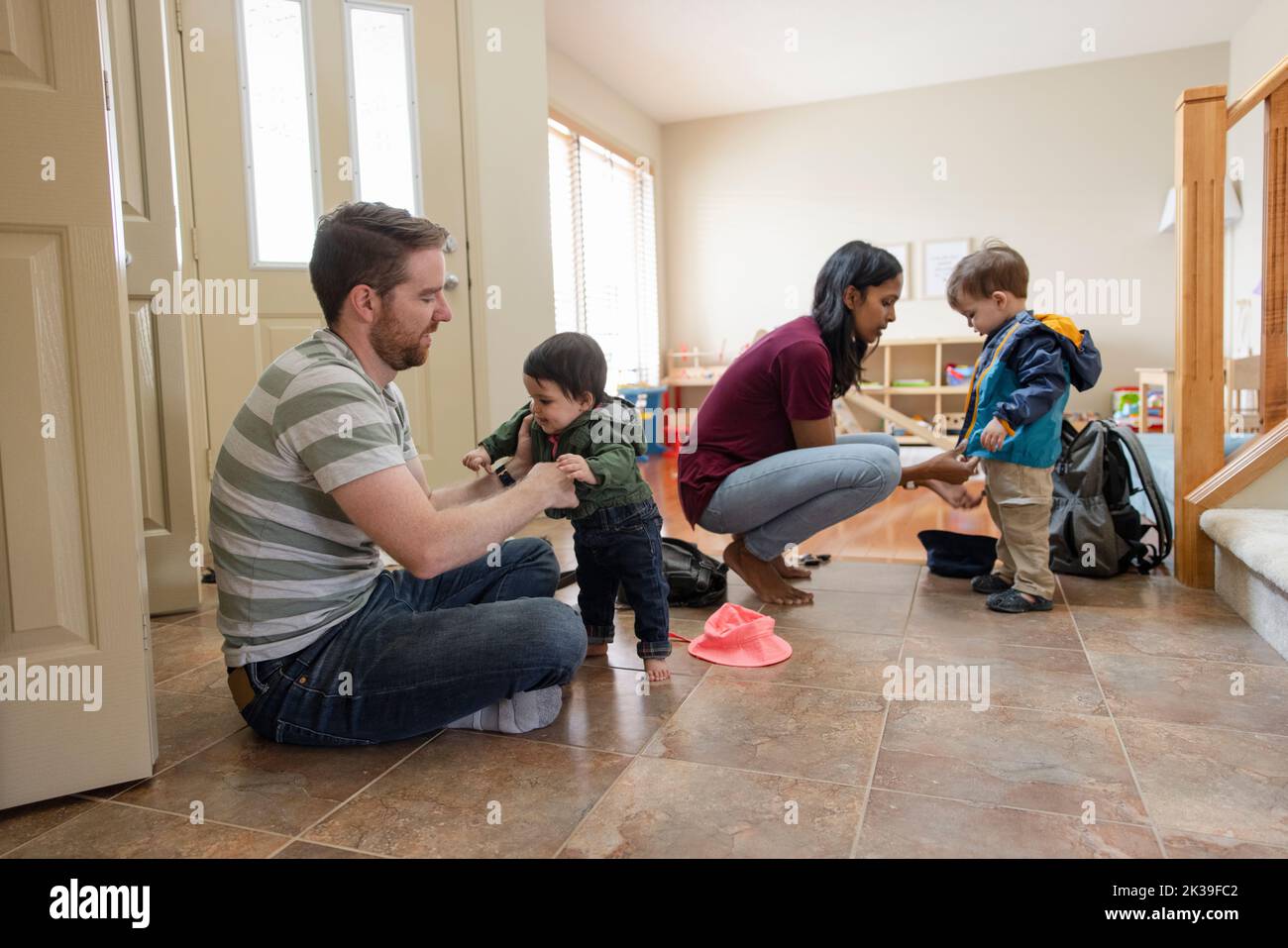 Parents helping kids with jackets in entryway Stock Photo