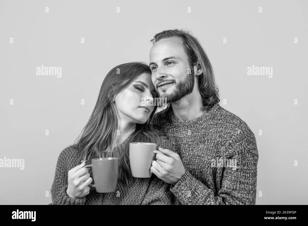 happy woman and man wear knitted clothes in winter and drink tea from