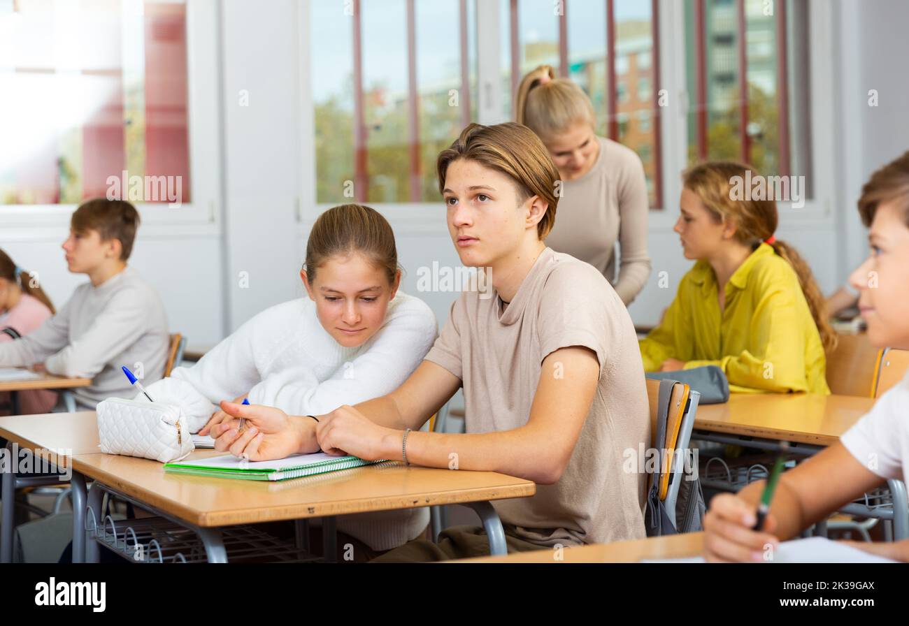 Schoolgirl peeks in a boys notebook during classes in school class Stock Photo