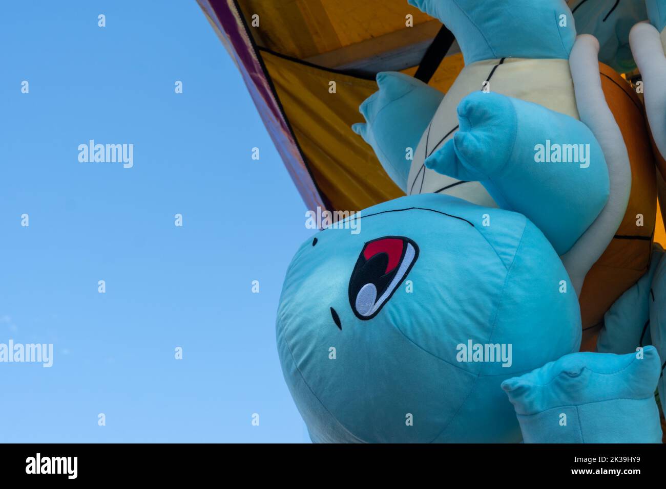 Calgary, Alberta, Canada - July 16, 2022: A Squirtle pokemon stuffed plush toy offered as a prize for winning a carnival game, shown hanging upside do Stock Photo