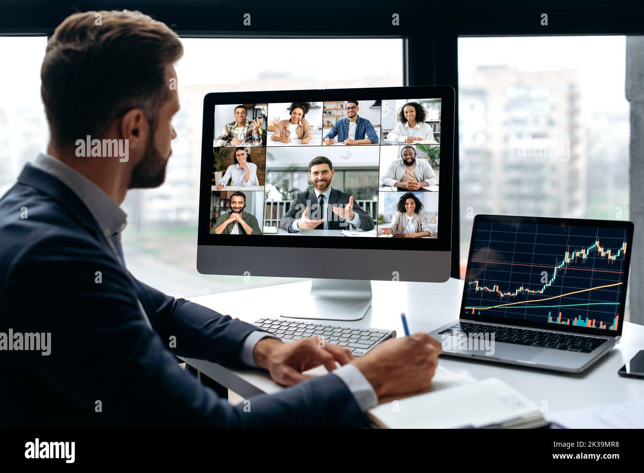 Motivated successful male stock investor, trader, listens to an online webinar on the topic of trading, investment. Group of multiracial people on computer screen. Online video course on investments Stock Photo