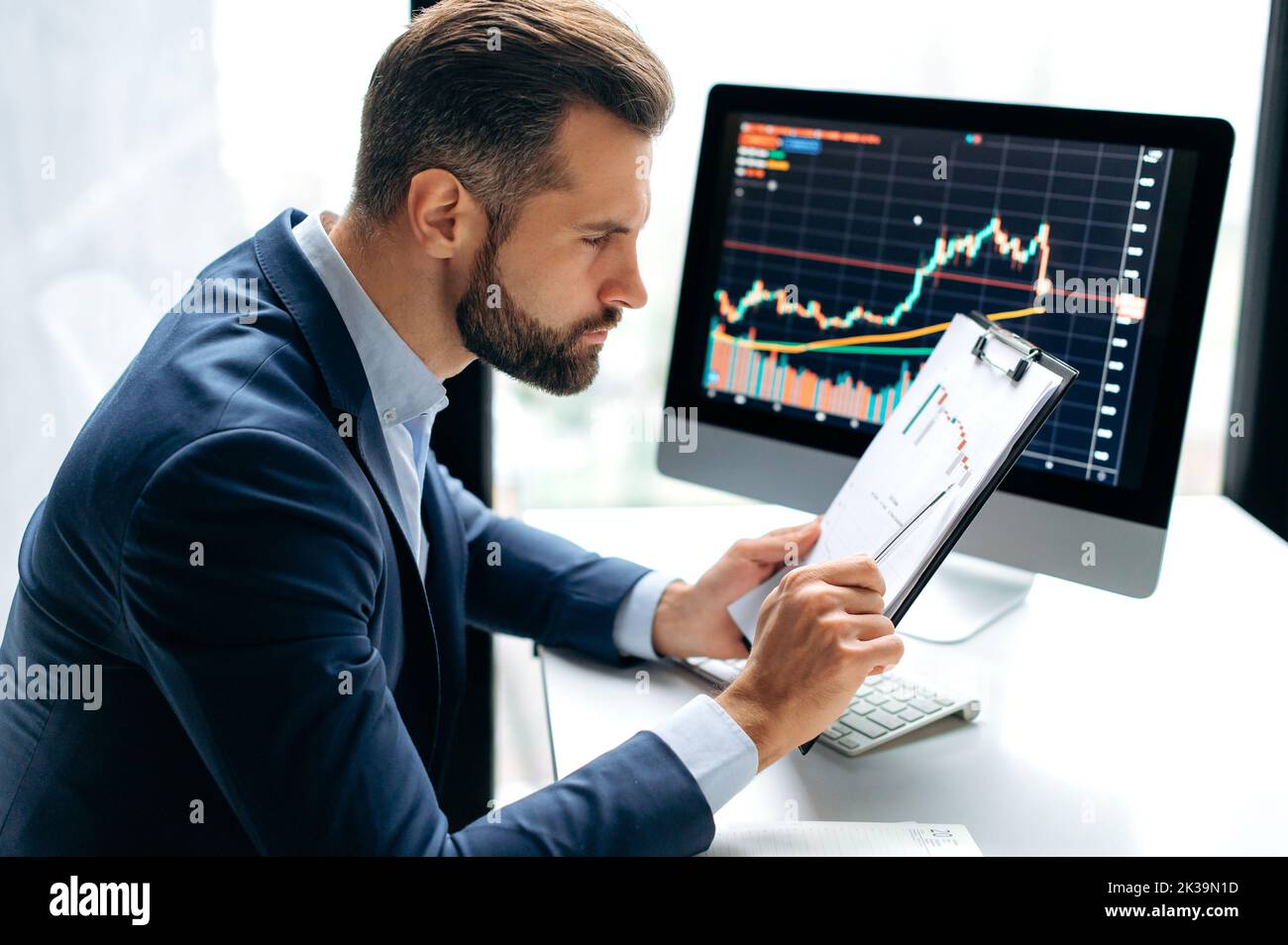 Busy focused pensive smart successful caucasian male stock investor, broker, financial expert, sit at work desk, uses computer and charts, analyzes risks and prospects, rise or fall of cryptocurrency Stock Photo