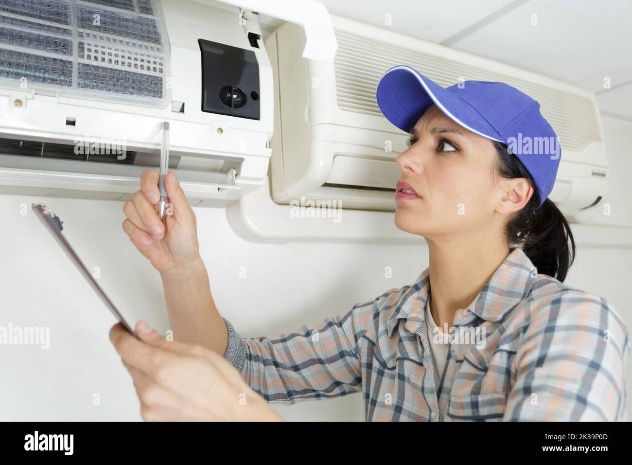 a young woman cleaning air conditioning system at home Stock Photo