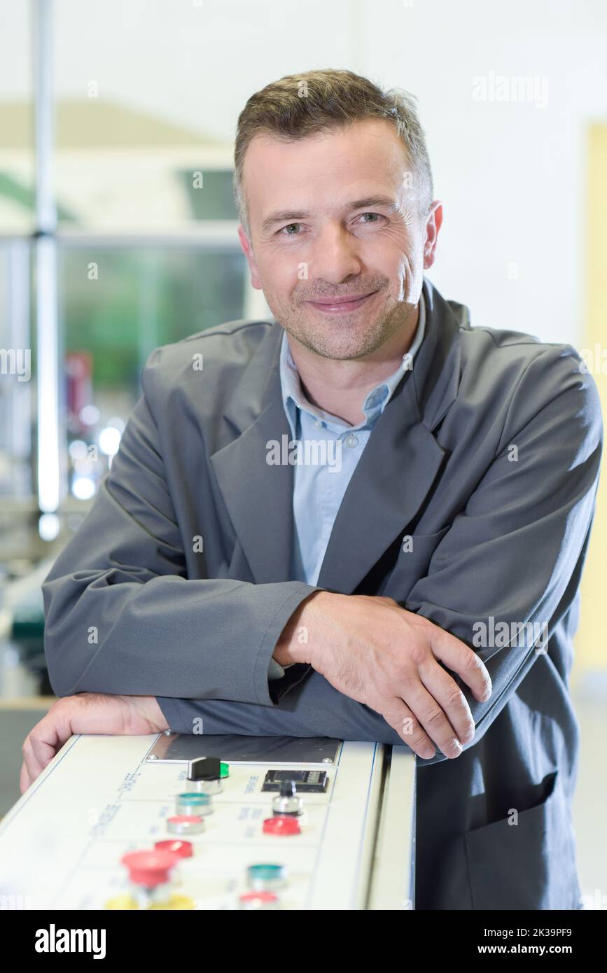 portrait of man in factory leaning on control panel Stock Photo - Alamy