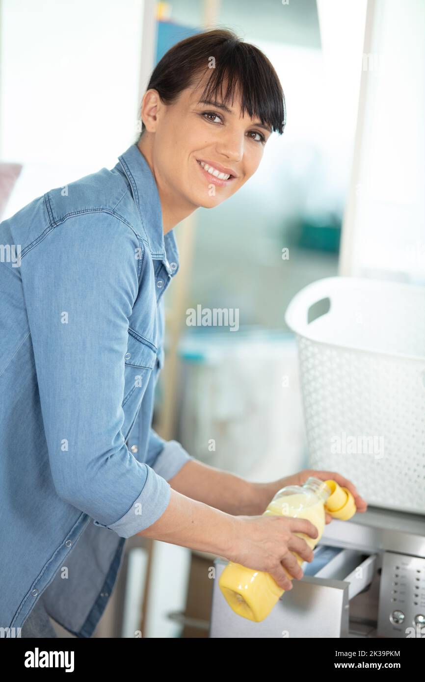 woman pouring fabric softener into washing machine drawer Stock Photo
