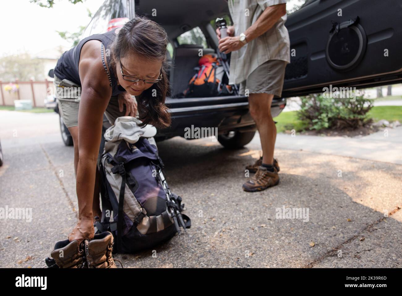Woman loading hiking boots and backpack into car in driveway Stock ...