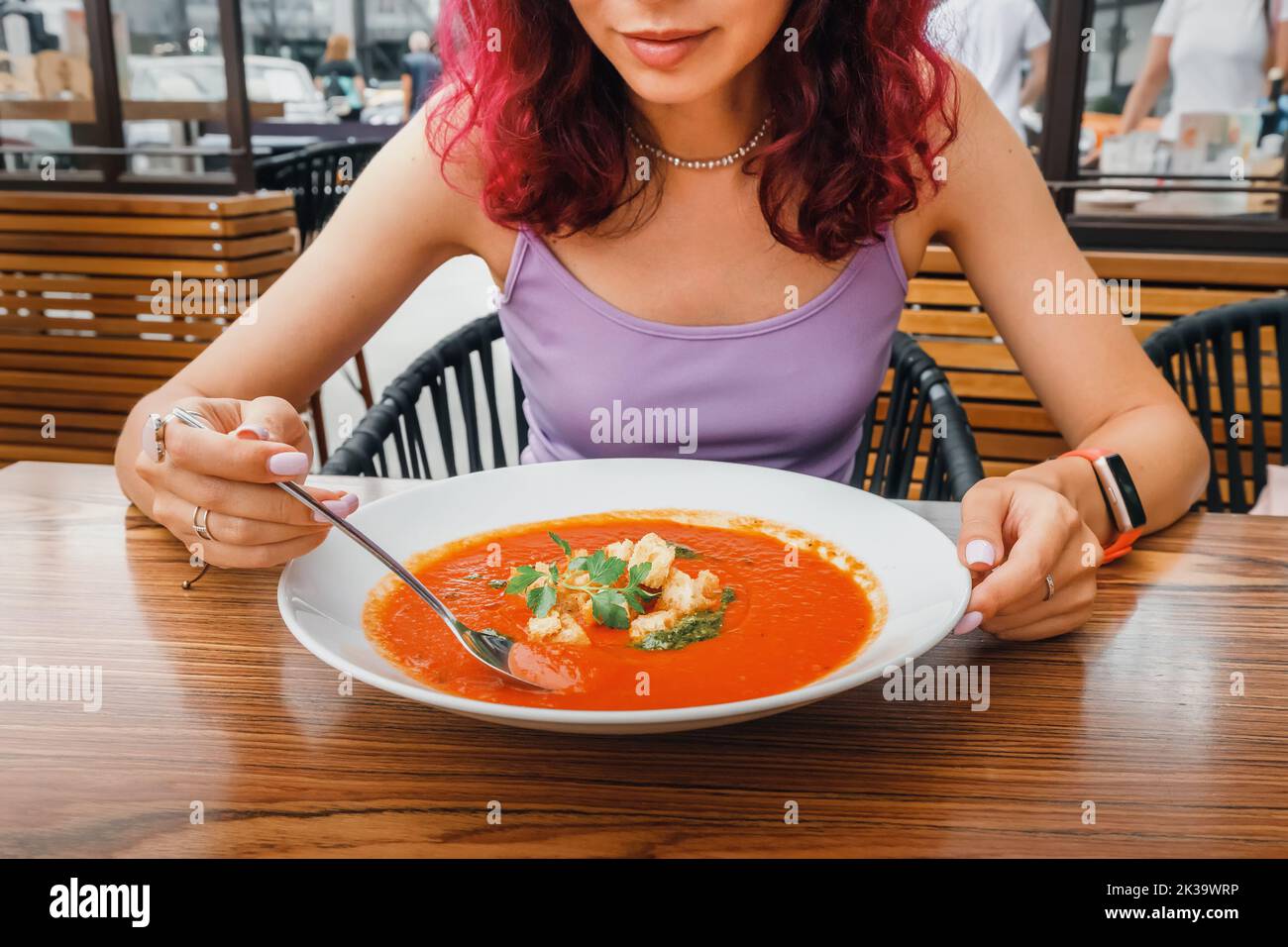Woman eating delicious tomato soup in cafe or restaurant. Vegetarian cuisine and healthy vegetable diet. Dinner and meal with organic products Stock Photo