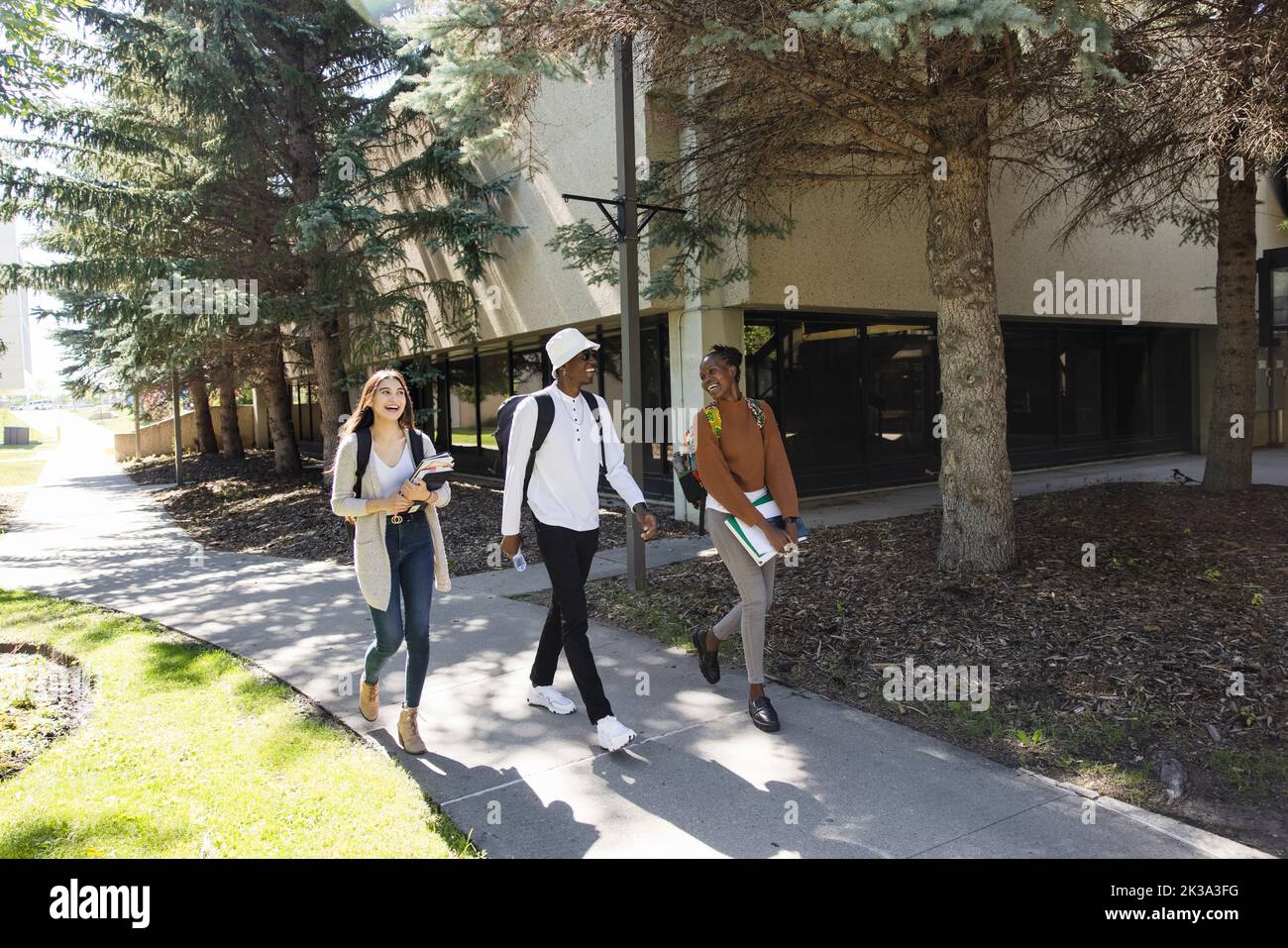 Happy college students walking on campus sidewalks Stock Photo