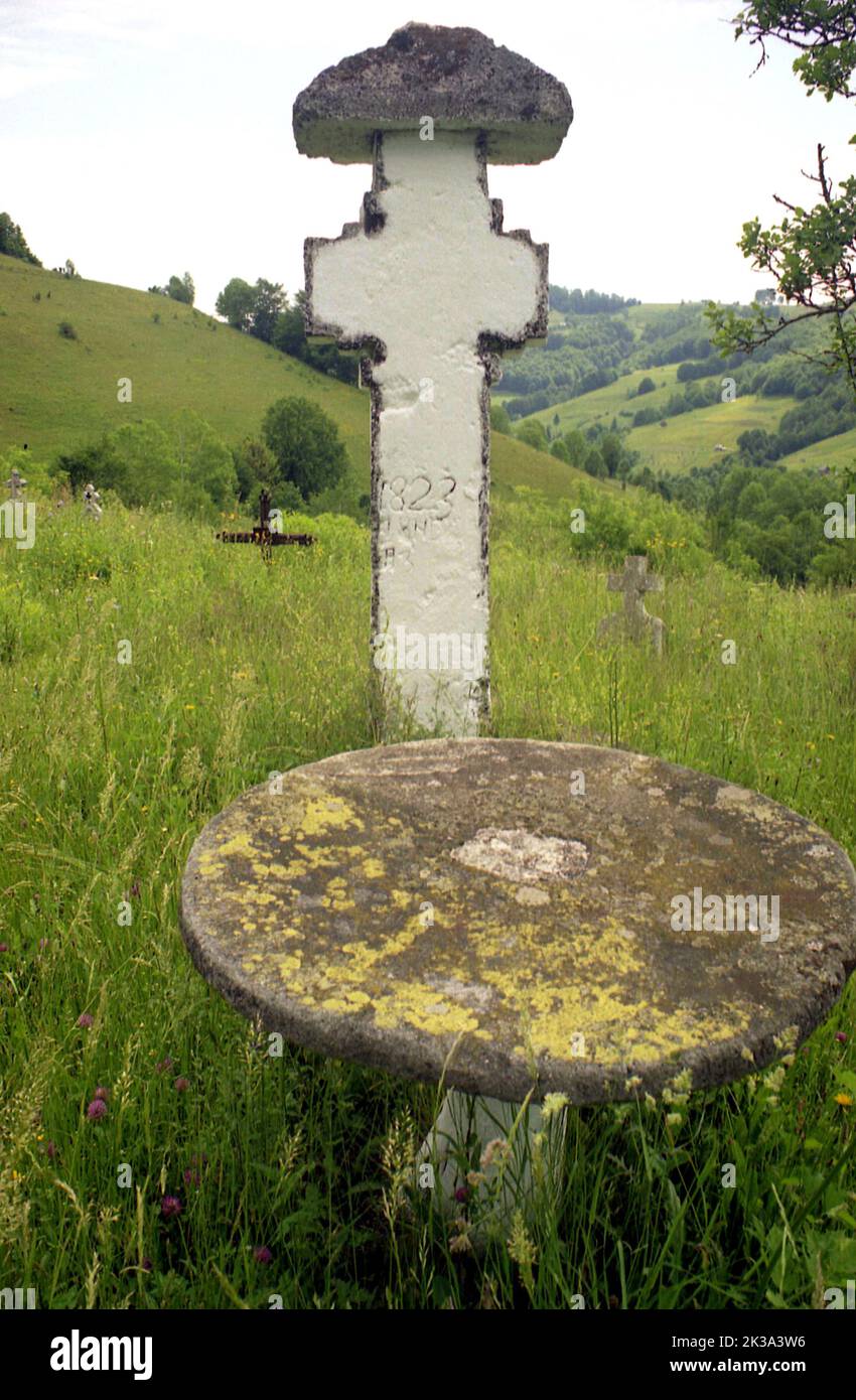 Old cemetery in Alba County, Romania, with a stone cross from the early 19h century. Stock Photo