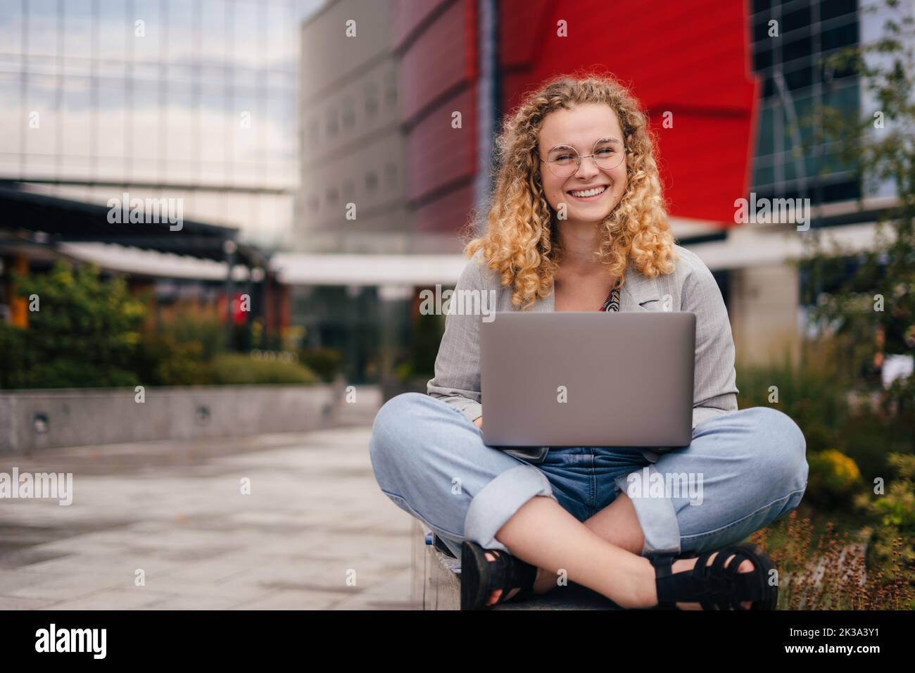 Front view of a smiling student girl wearing eyewear using laptop ...