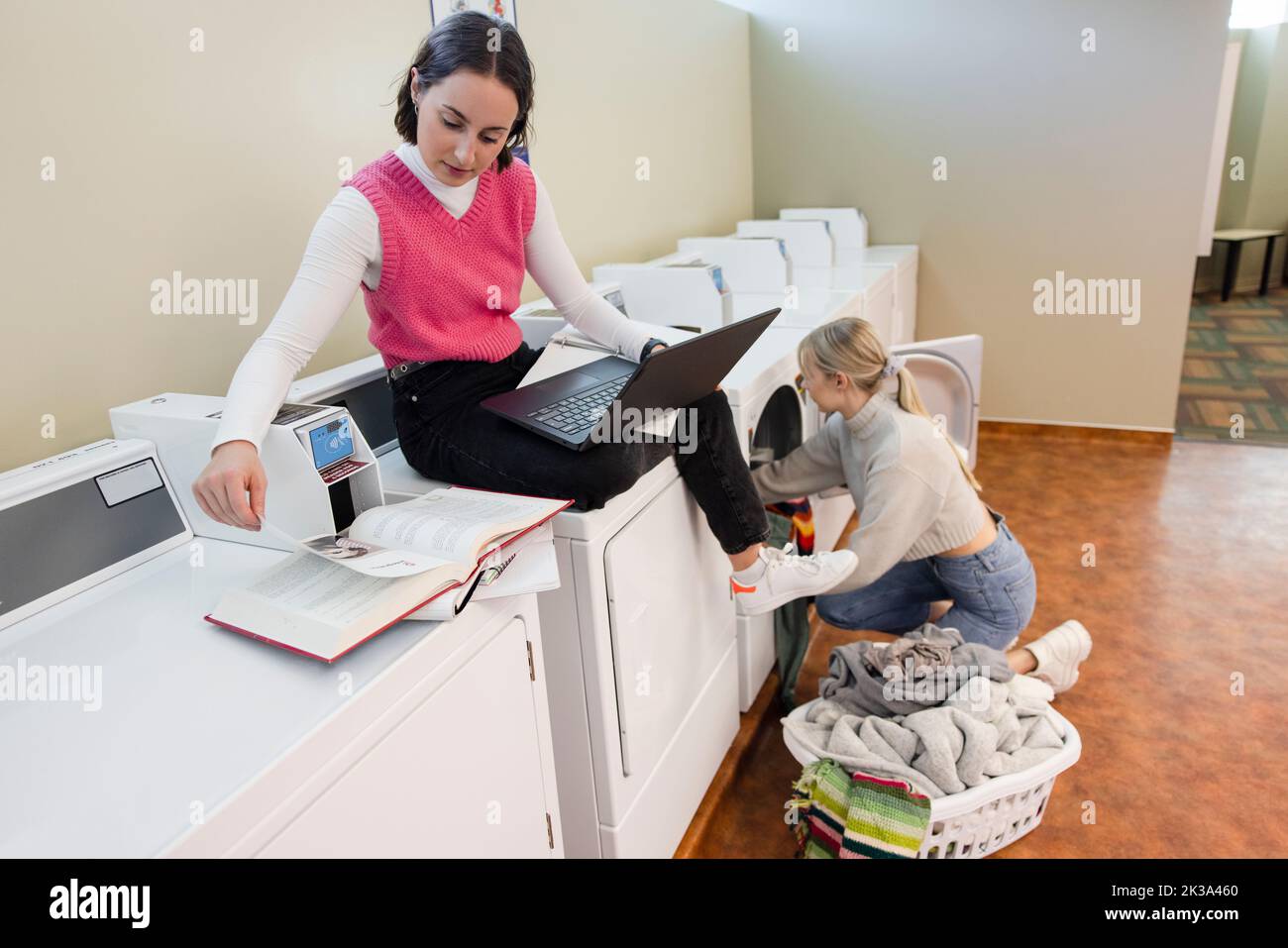Young female college students studying and doing laundry in dormitory