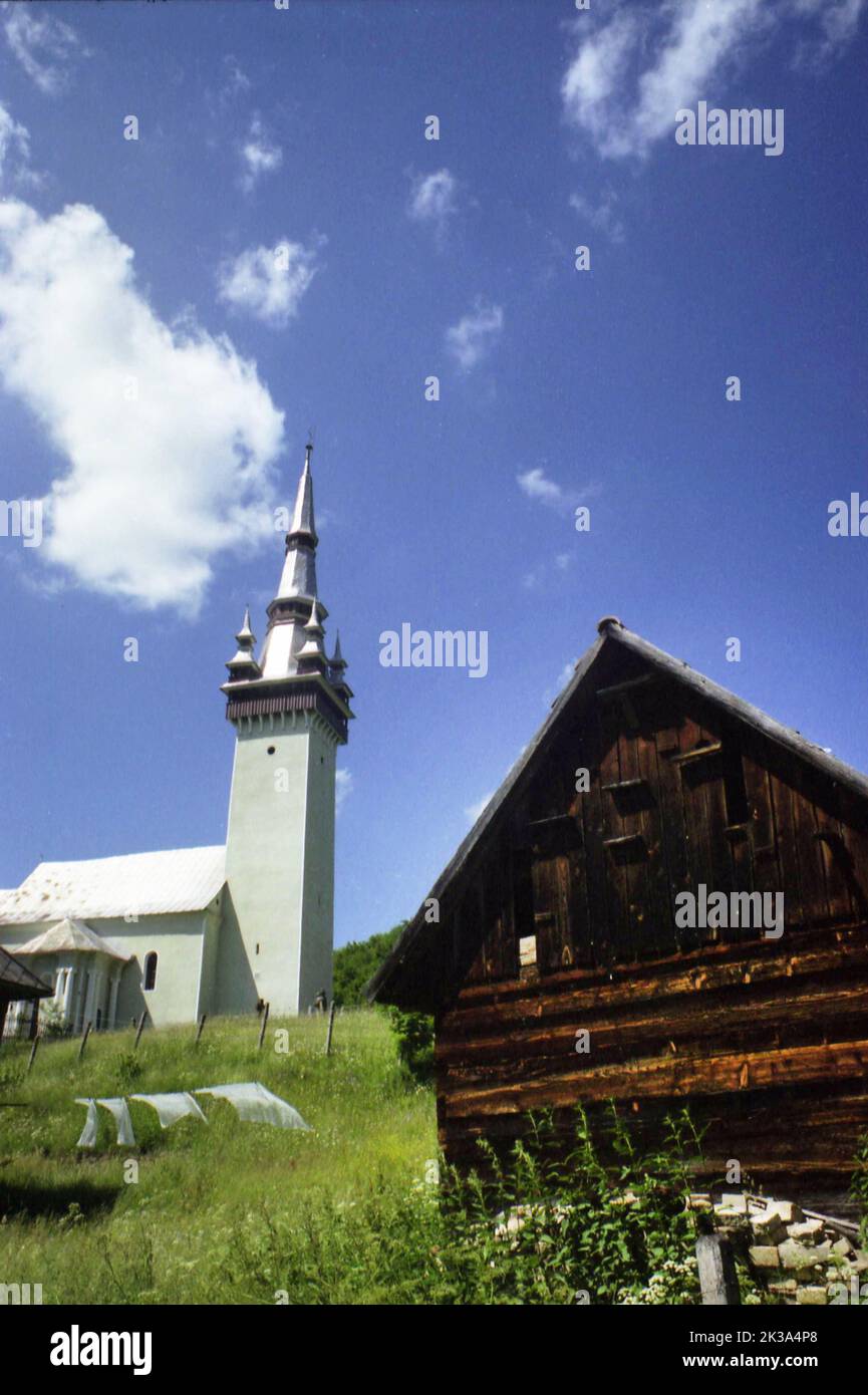 Roșia Montana, Alba County, Romania, approx. 1999. Property with a wooden barn and the Greek-Catholic church (b. 1741) up the hill. Stock Photo