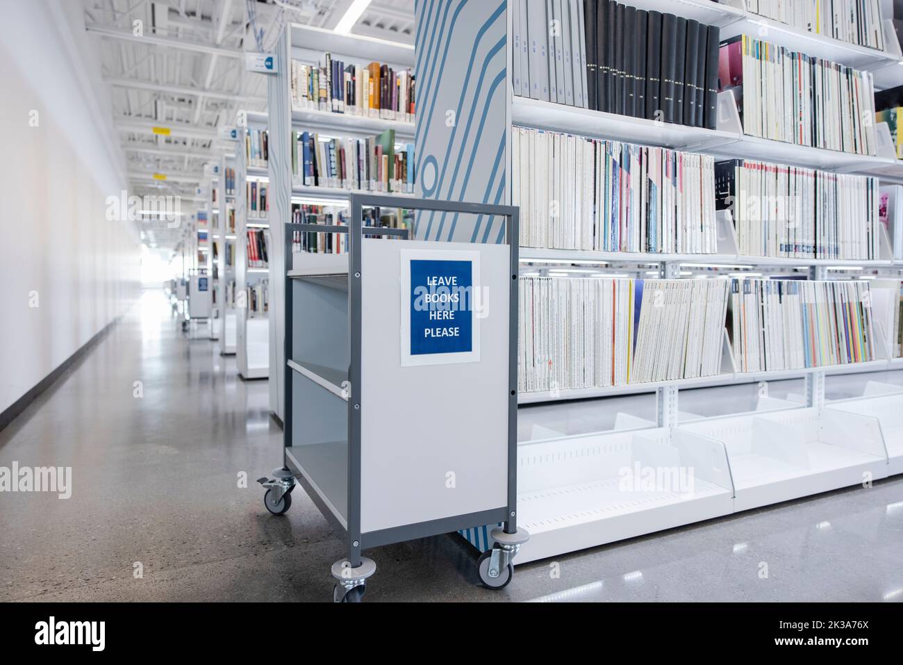 Book cart with sign at bookshelf in empty college library Stock Photo