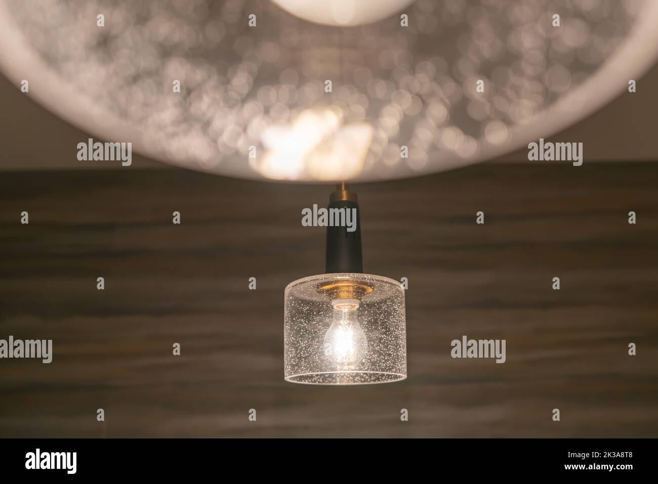 Hanging incandescent light bulb with tungsten filaments with a wall background. Stock Photo