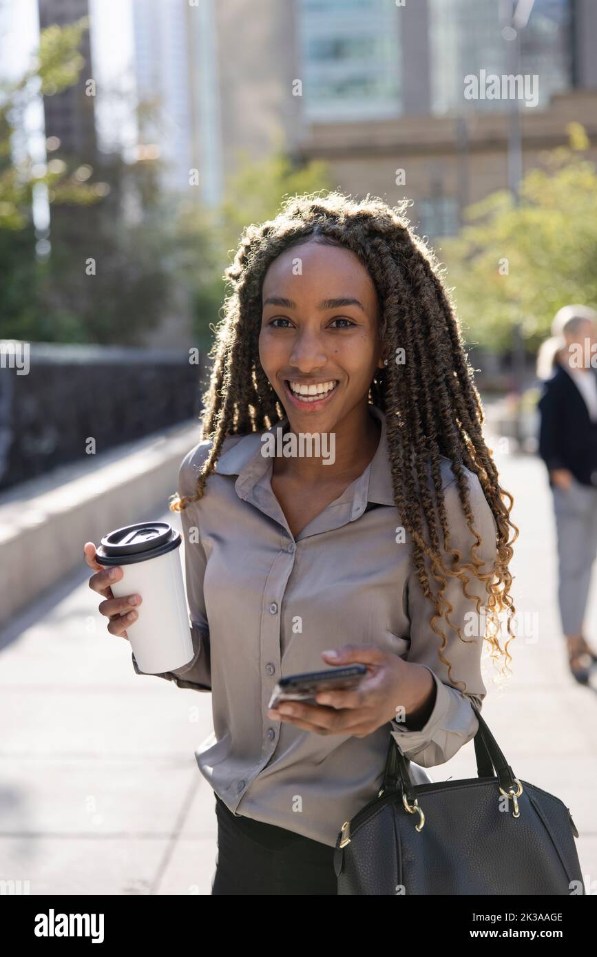 Portrait of black woman on phone with coffee Stock Photo