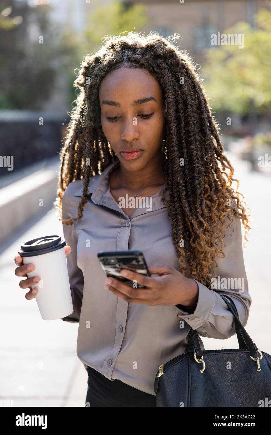 Portrait of black woman on phone with coffee Stock Photo