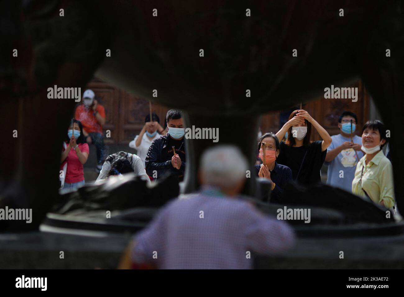People wearing face masks worship at the Buddhist Jing'an Temple, following the coronavirus disease (COVID-19) outbreak, in Shanghai, China, September 26, 2022. REUTERS/Aly Song Stock Photo