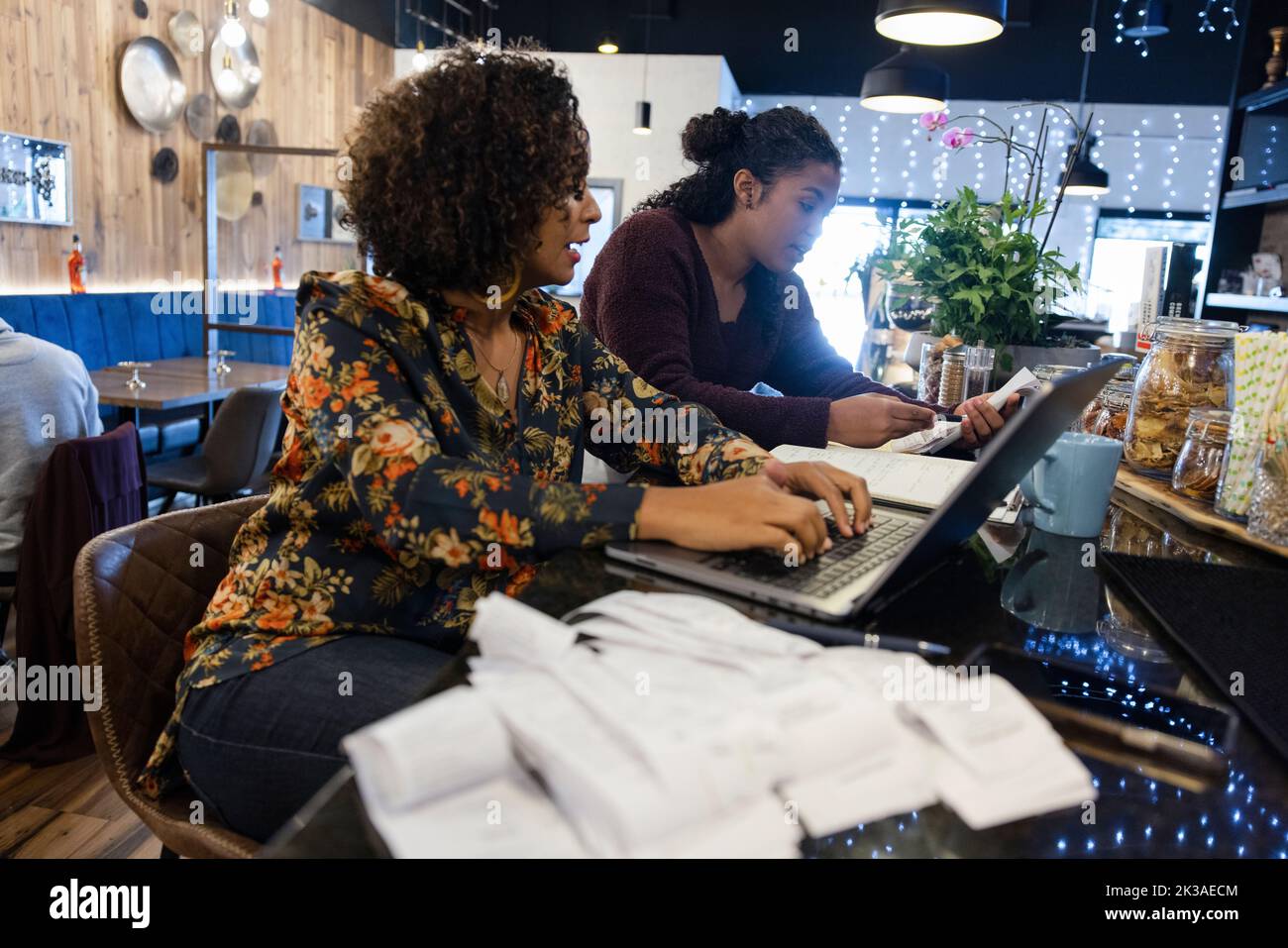 Restaurant manager and colleague working with laptop on bar counter Stock Photo