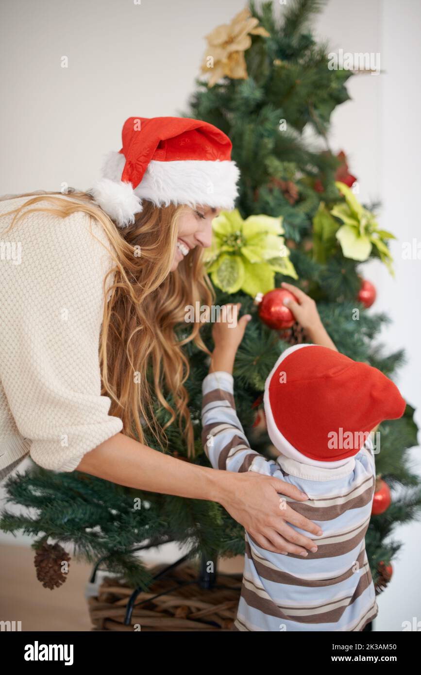 My favorite part of the holiday. a young boy decorating a christmas tree with his mothers help. Stock Photo