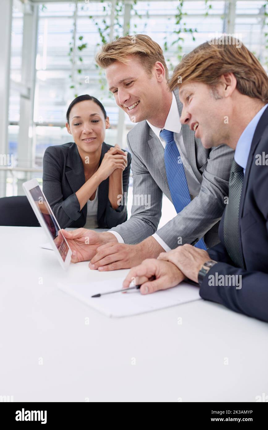 Weve made some great progress in this department. A young businessman showing his colleagues something on a digital tablet. Stock Photo