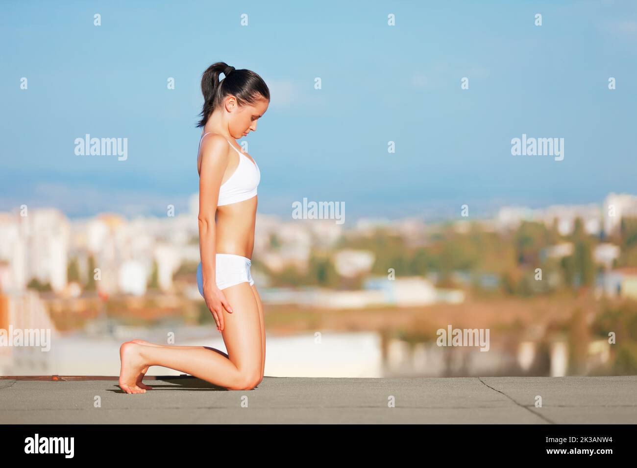 Finding her center with solitutde. an attractive young woman in workout gear doing yoga on a rooftop. Stock Photo