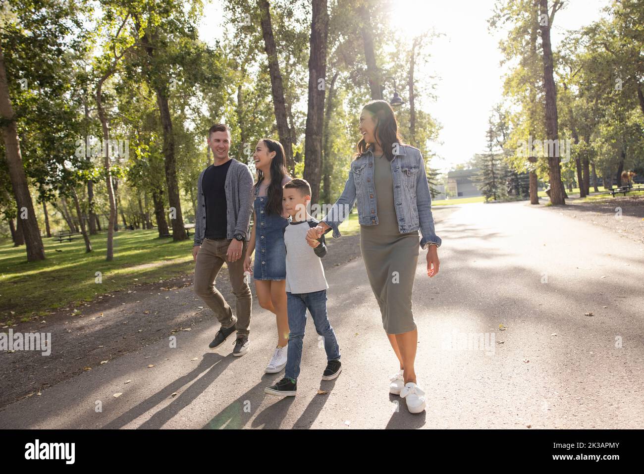 Happy family walking on sunny footpath in park Stock Photo