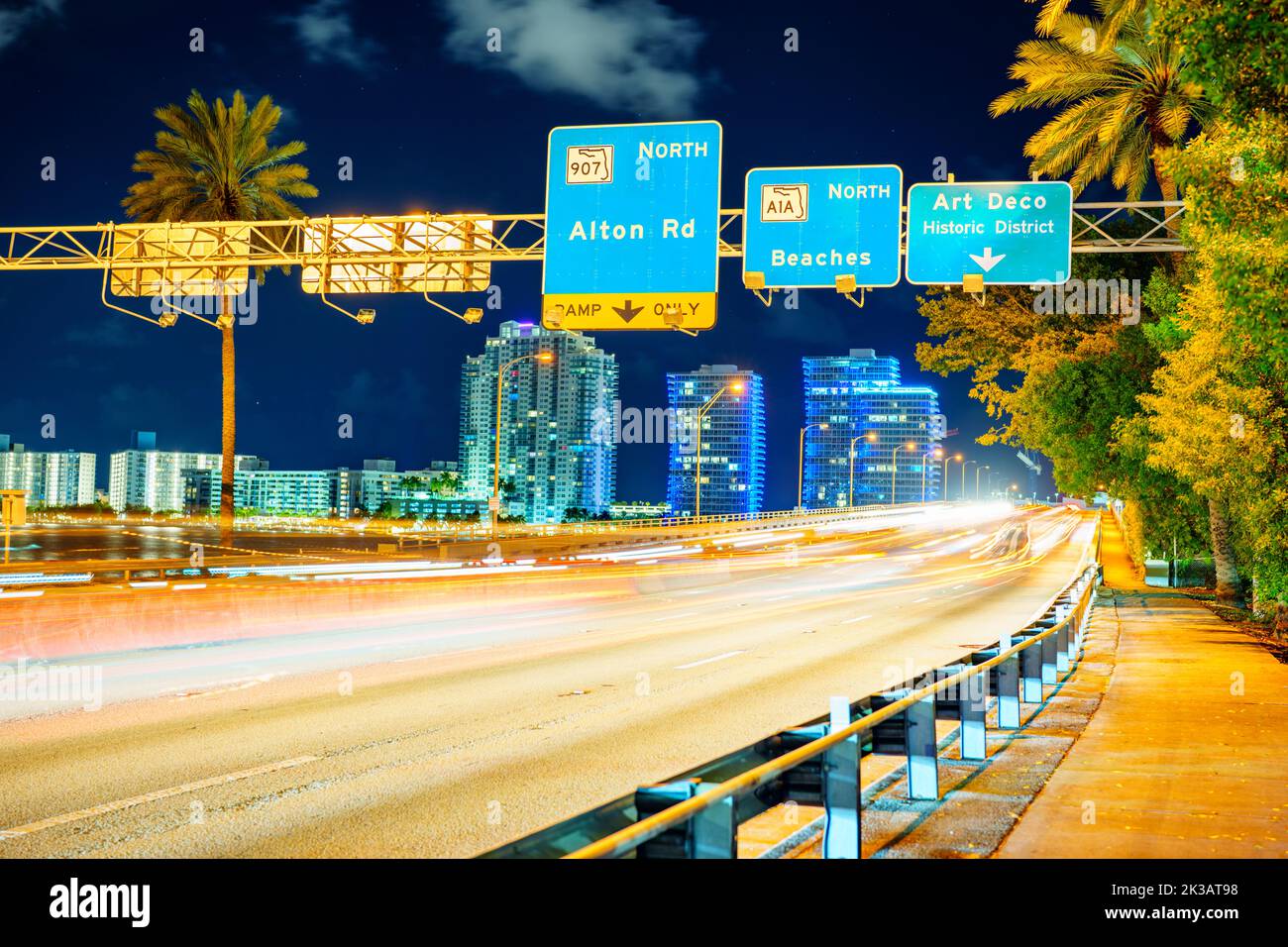 Night road sign to Miami Beach with light trails Macarthur Causeway Stock Photo