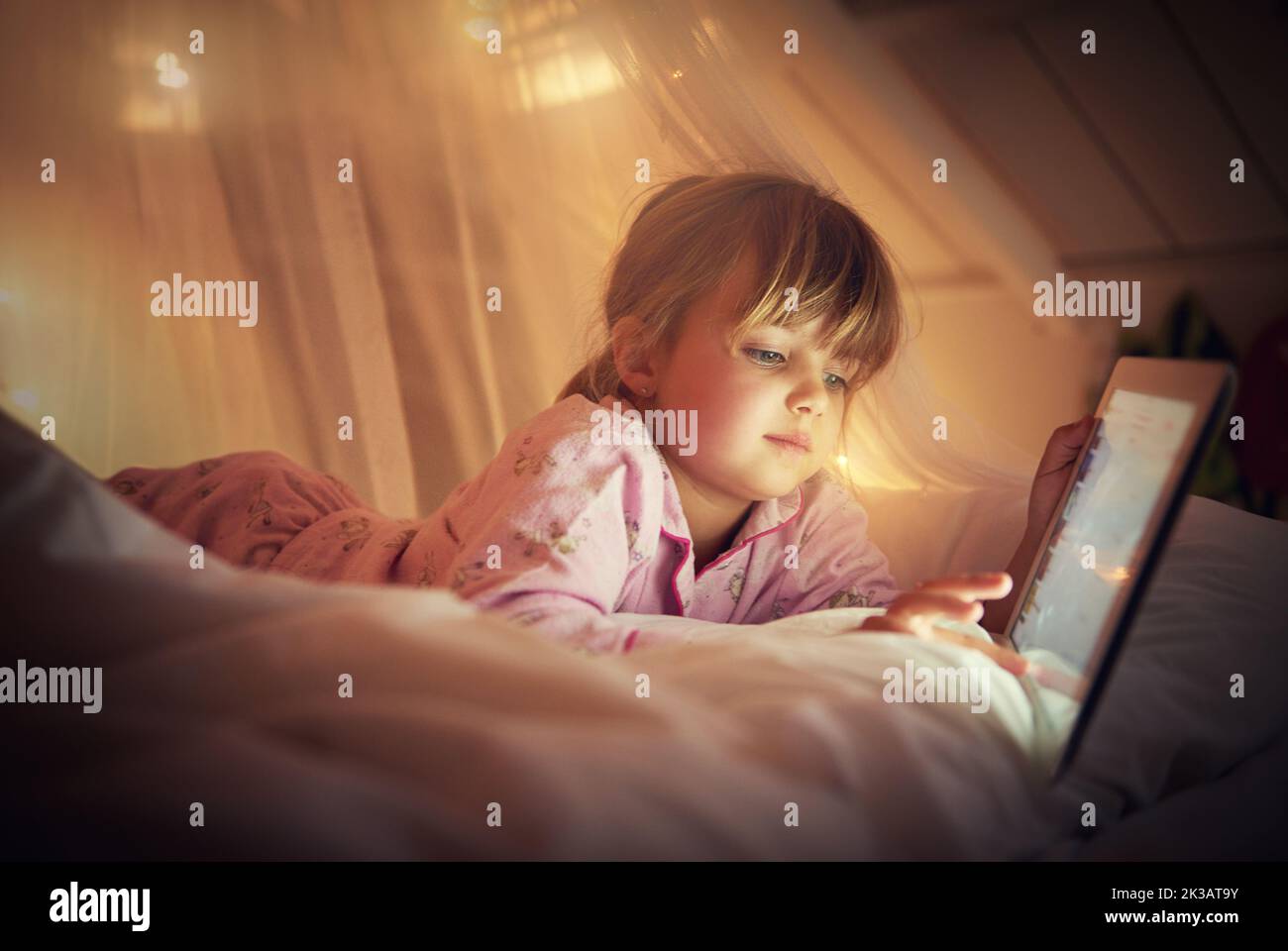 I read past my bedtime. A young girl lying on her bed while using a