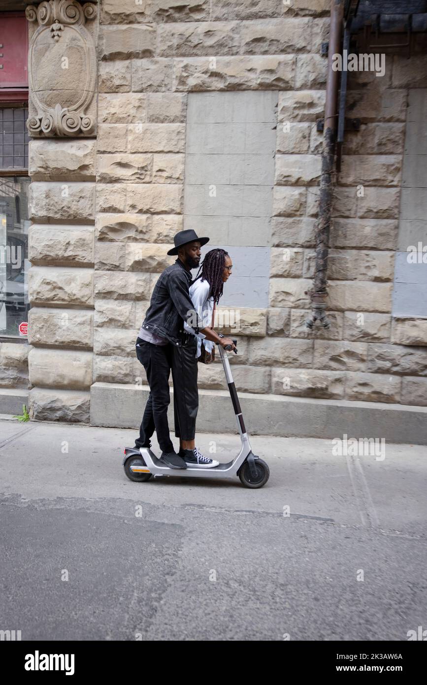 Couple riding electric push scooter on urban sidewalk Stock Photo Alamy