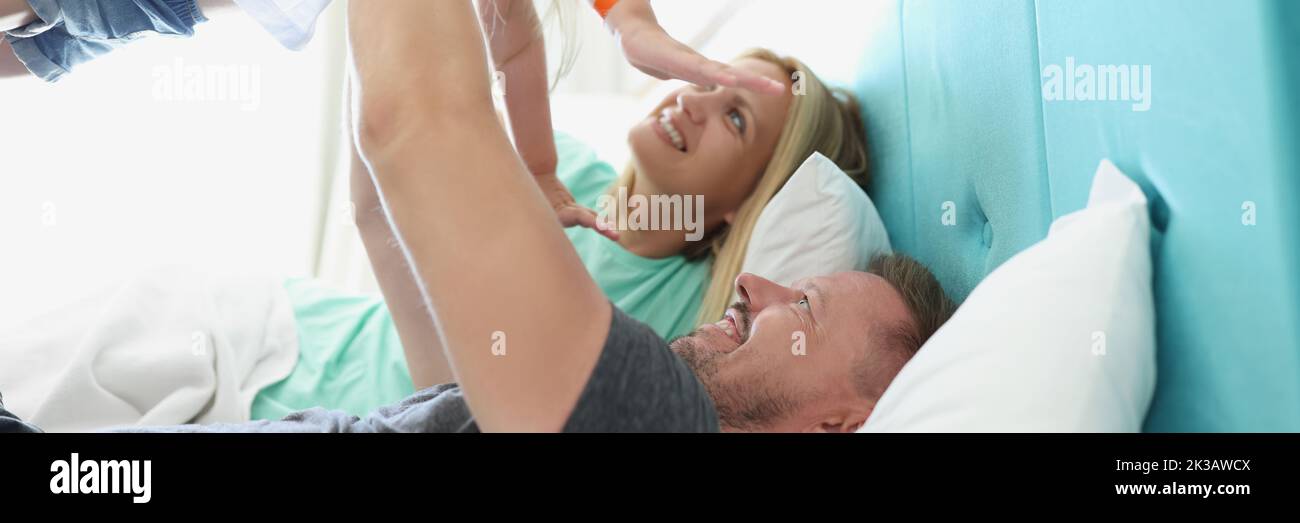 Lying on the bed, the parents lifted the child up Stock Photo