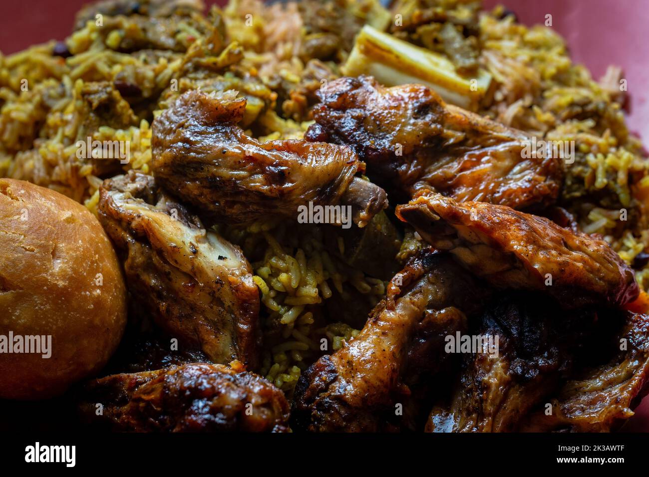 Traditional Jamaican jerk chicken wings, curried goat and fried dumpling with rice and peas Stock Photo