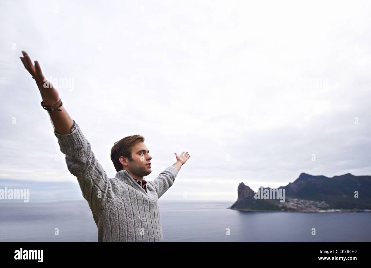 Basking in natures glory. A young man standing with his arms raised against an ocean view. Stock Photo