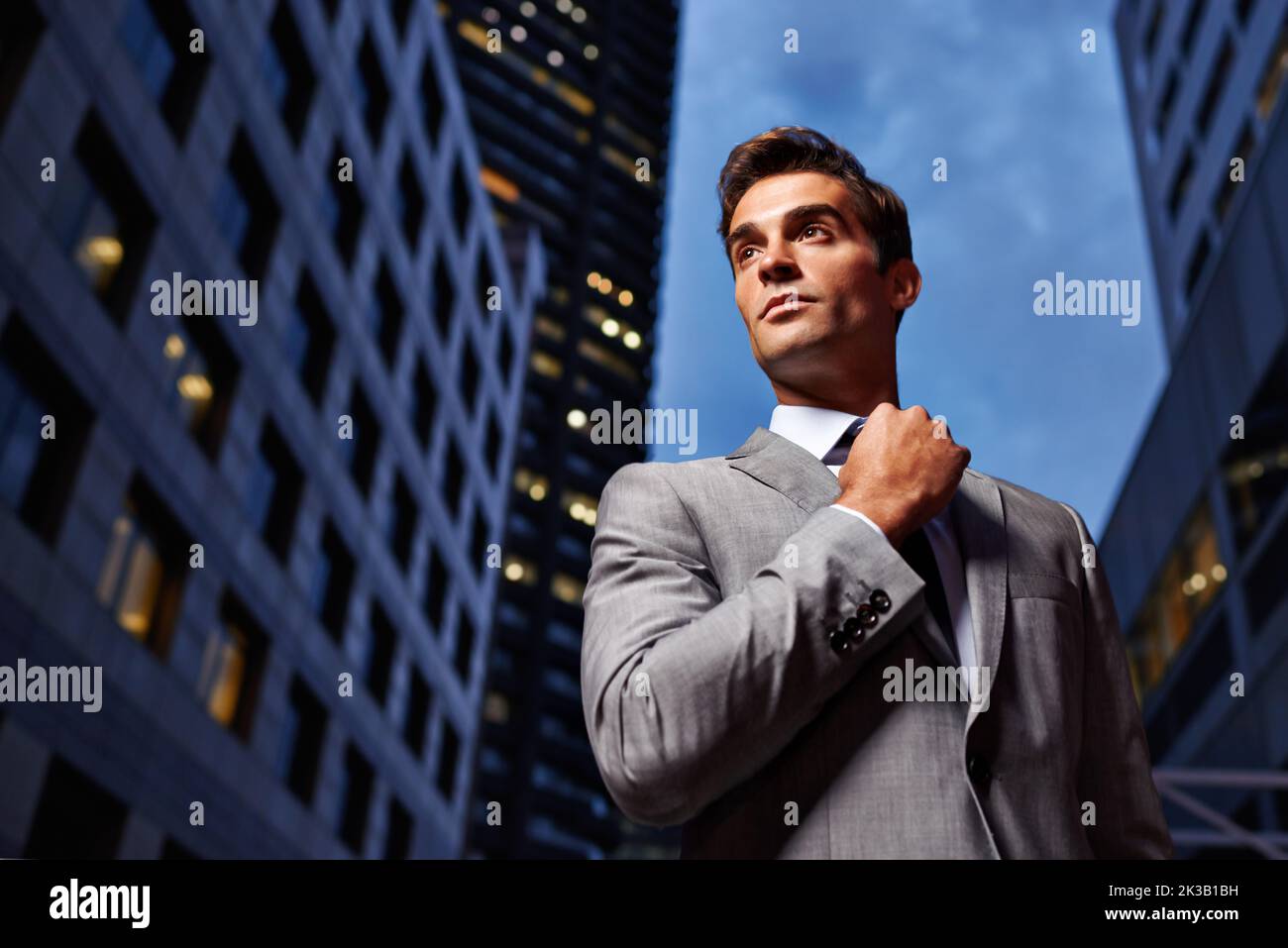 Twilight business style. a handsome businessman in a suit standing in a city setting at night. Stock Photo