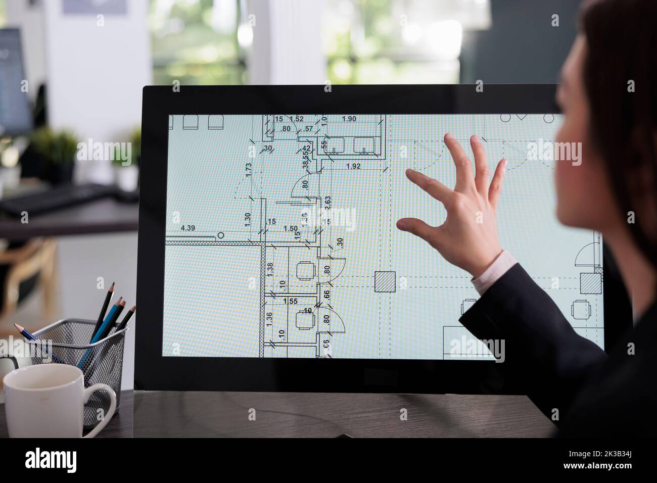 Real estate studio employee working in room floor planner software, zooming in apartment plan with touchscreen. Cad blueprints on computer monitor screen, designer drafting architectural sketch. Stock Photo