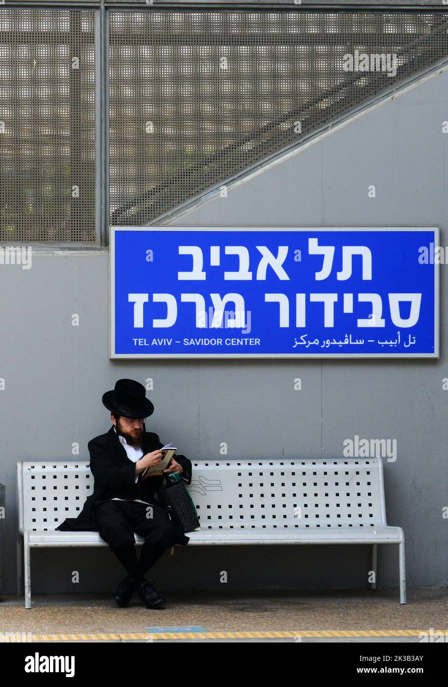 A religious Jewish man by the sign of Tel-Aviv Savidor Center railway station. Tel Aviv, Israel. Stock Photo