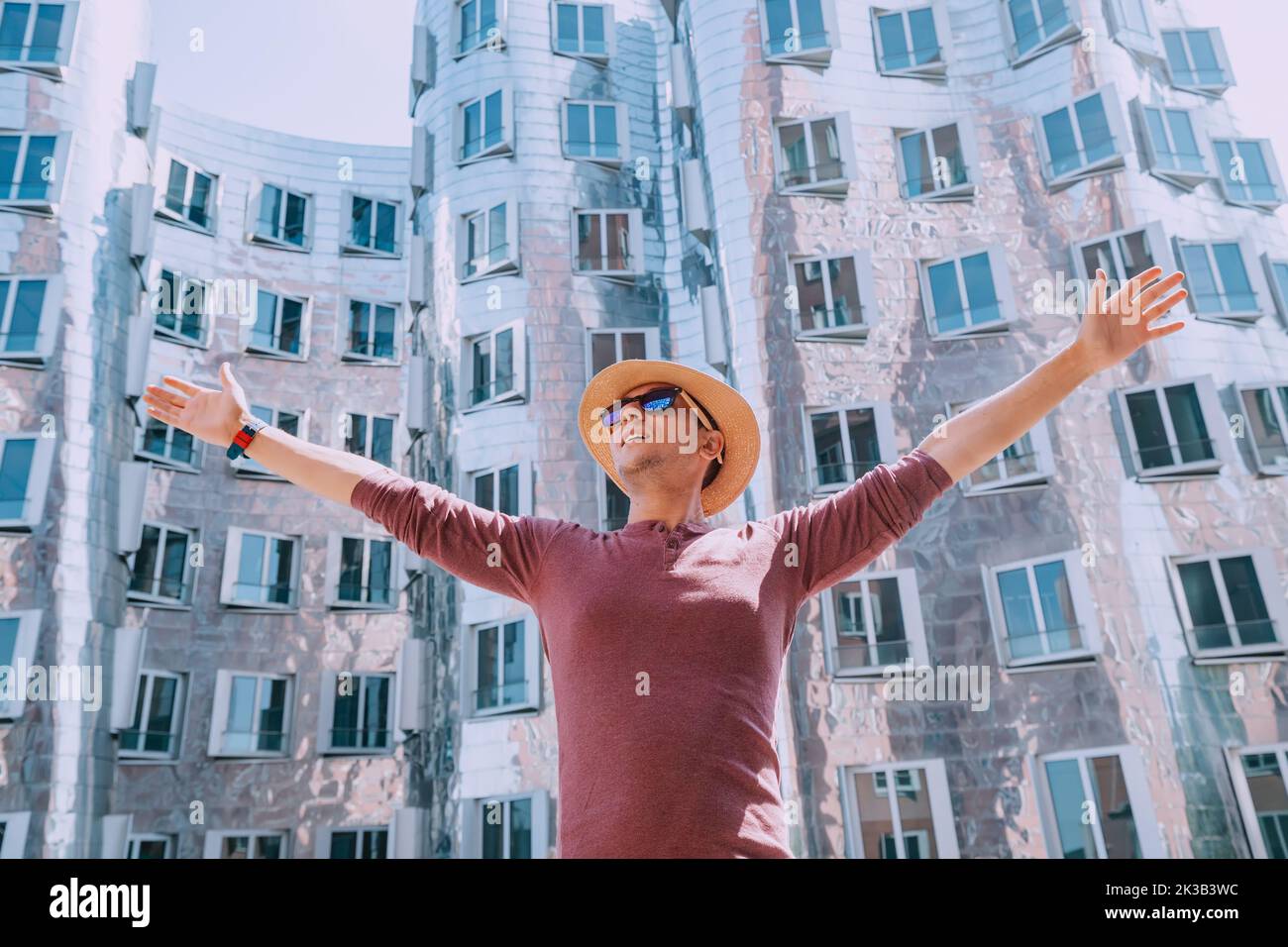 Traveler man in hat admiring view at the Zollhof unusual modern architecture buildings in Media Harbor - Dusseldorf, Germany. Dancing houses and trave Stock Photo