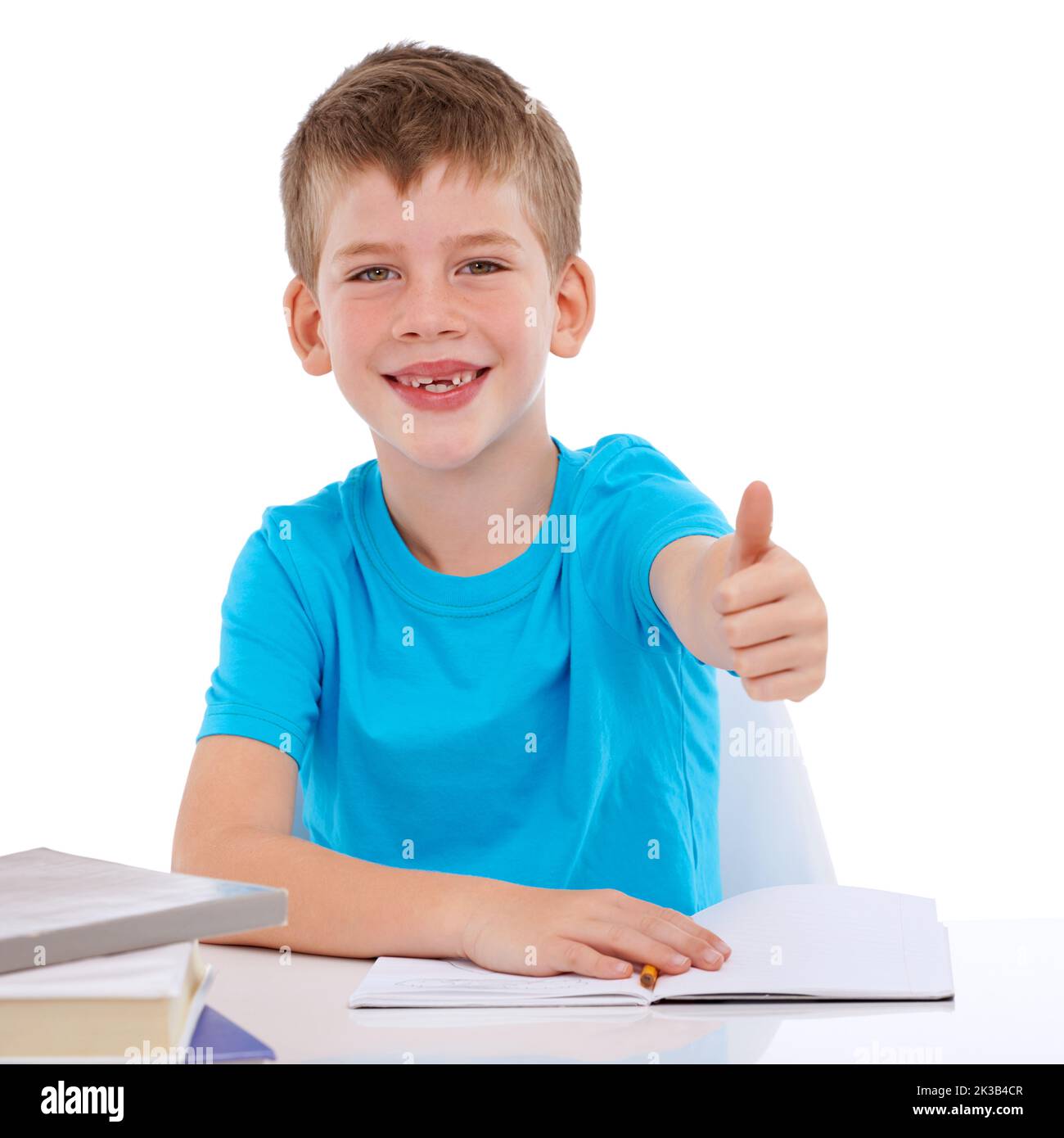 I like studying hard. Portrait of a young boy sitting with his homework holding a thumbs up sign. Stock Photo