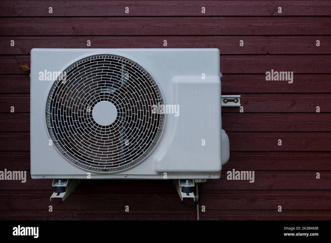 save electricity consumption with a white heat pump unit mounted on a red wood panel, Denmark, September 22, 2022 Stock Photo