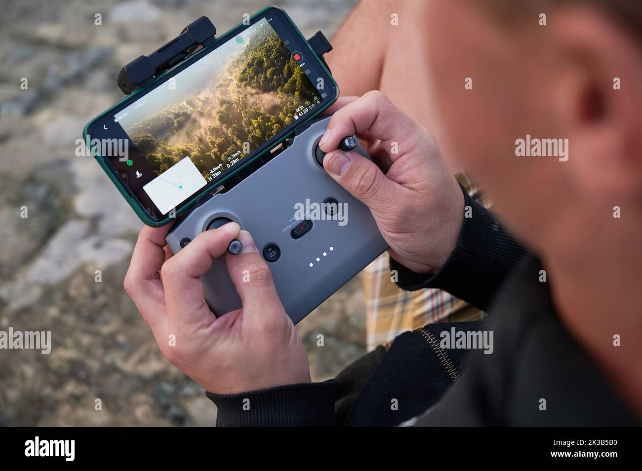 Close up man operating drone using remote controller. Man using drone at sunset for photos and video making Stock Photo
